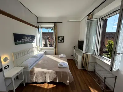 a bedroom with a bed and a desk and two windows at Villa Lanusei in Rome