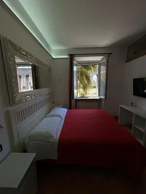 a bedroom with a red bed and two windows at Villa Lanusei in Rome