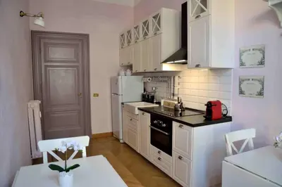 a kitchen with white cabinets and a white refrigerator at Trastevere elegant apartment in Rome