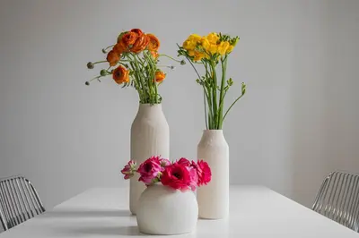 three white vases with flowers on a table at Caracciolo Vatican Apartment in Rome