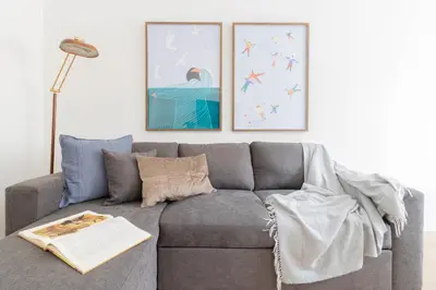 a living room with a gray couch with two pictures at Caracciolo Vatican Apartment in Rome