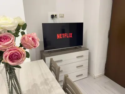 a television on top of a dresser with a table and flowers at Valerias Nest Elegant Apt with WiFi and Charm in Rome