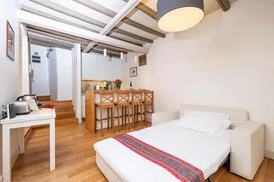 a bedroom with a white bed and a kitchen at Casa Di Armando al Pantheon in Rome
