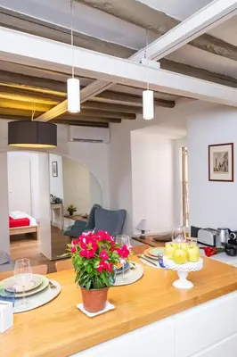 a kitchen and living room with a wooden table with flowers at Casa Di Armando al Pantheon in Rome