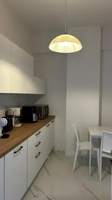 a kitchen with white cabinets and a table and a light at Bella Roma Stay in Rome