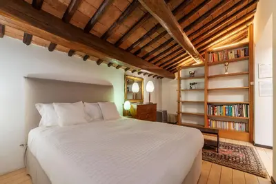 a bedroom with a white bed and a book shelf at Orange Room with bathroom and Shared Terrace in Rome