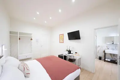 a white bedroom with a bed and a desk at Domus Giulio Guest House in Rome