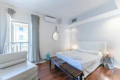 a white bedroom with a bed and a chair at Vatican Pixel Apartments in Rome