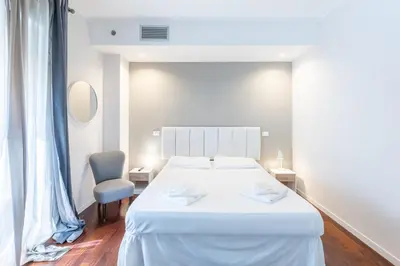 a white bedroom with a large white bed and a chair at Vatican Pixel Apartments in Rome