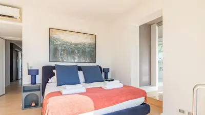 a white bedroom with a large bed with blue pillows at EasyTopStay - Rome from above Apt with a view in Rome