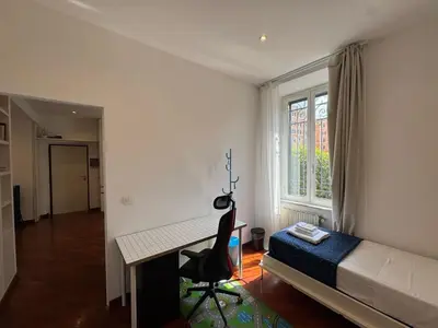 a bedroom with a desk and a bed and a window at St John Apartment in Rome in Rome