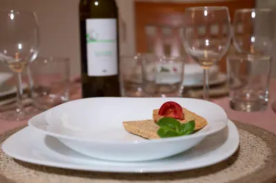 a white plate with a sandwich and a bottle of wine at RomAntica Laterano in Rome
