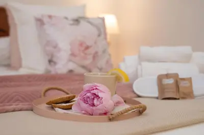 a tray with a pink flower and a cup on a bed at RomAntica Laterano in Rome