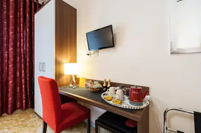 a hotel room with a table and a red chair at Vatican Golden Rooms in Rome