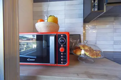 a red microwave on a counter with a bowl of fruit at Clodia Holiday Home in Rome