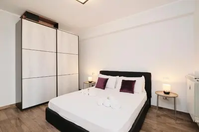 a bedroom with a large white bed with two tables at A few minutes from the Colosseum - Free Wi-Fi & Netflix in Rome