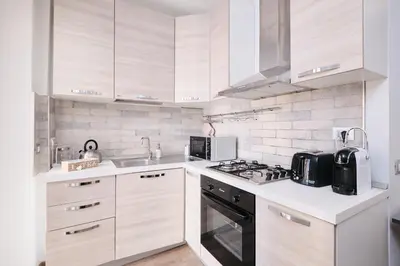 a kitchen with white cabinets and a stove top oven at A few minutes from the Colosseum - Free Wi-Fi & Netflix in Rome