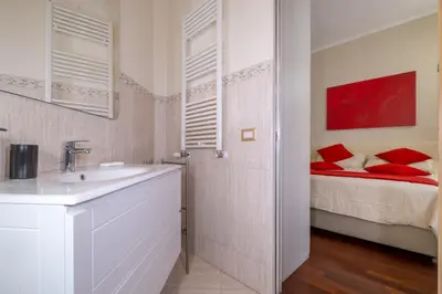 a bathroom with a sink and a bed with red pillows at Trevi Fountain big apartment in Rome