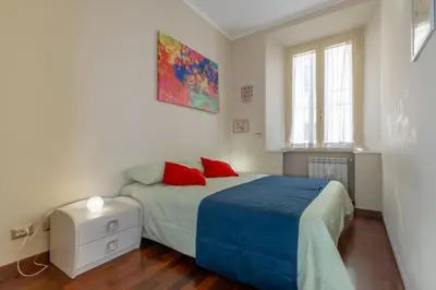 a bedroom with a bed with blue sheets and red pillows at Trevi Fountain big apartment in Rome