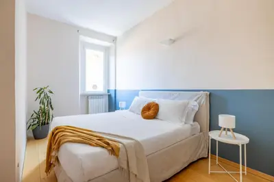 a bedroom with a white bed with a blue wall at Boschetto Apt - Homkeey Apartments in Rome