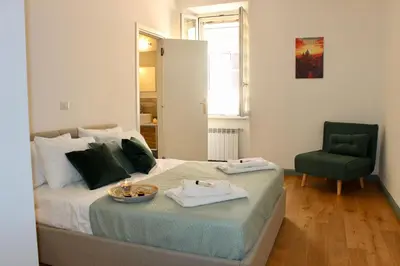 a bedroom with a bed and a green chair at Hideaway 65 - Home by St Peter's in Rome
