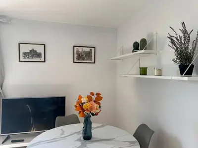 a vase of flowers on a table with a tv at Rooftop via Appia Nuova, Roma in Rome
