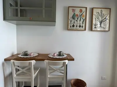 a kitchen with a table and two white chairs and a counter at Rooftop via Appia Nuova, Roma in Rome