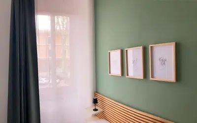 four framed drawings on a green wall next to a window at Casa Ferrari in Rome