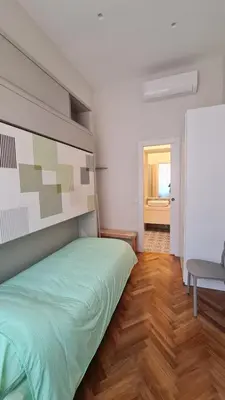 a bedroom with a green bed and a wooden floor at Jolegrè all'Opera in Rome