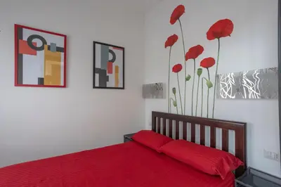 a bedroom with a red bed with red sheets and flowers at Attic Candia - Vatican Museum in Rome