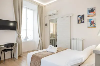 a white bedroom with a bed and a desk at Bottega Artistica Guest House in Rome