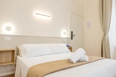 a white bed with white sheets and pillows on it at Bottega Artistica Guest House in Rome