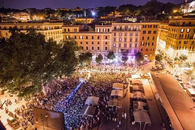 a large crowd of people in a city at night at NOSTROMONDO San Cosimato Trastevere Place in Rome