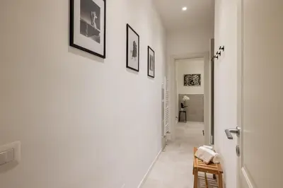 a hallway with white walls and pictures on the wall at NOSTROMONDO San Cosimato Trastevere Place in Rome