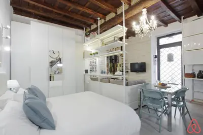 a bedroom with a white bed and a dining room at Your nest in Trastevere, the heart of Rome - Il vostro Nido nel cuore di Roma in Rome