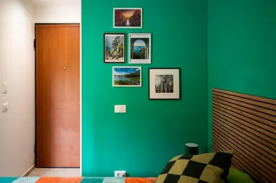 a green wall with pictures on it next to a bed at Sanlorenzo MaDa House in Rome