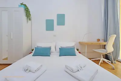 a white bed in a room with a desk and a chair at Casa Magnifica in Rome