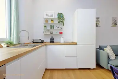 a kitchen with white cabinets and a blue couch at Casa Magnifica in Rome