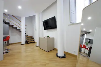 a living room with white walls and a flat screen tv at Trevi Suite Apartment - Barberini in Rome