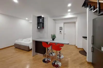 a kitchen with a counter and two red chairs in a room at Trevi Suite Apartment - Barberini in Rome