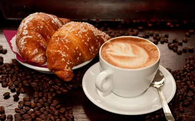 a cup of coffee and croissants and coffee beans at MICLAD Colosseum Guest House in Rome
