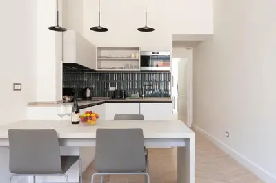 a kitchen with white cabinets and a white island with chairs at Residenza Foraggi 83 in Rome
