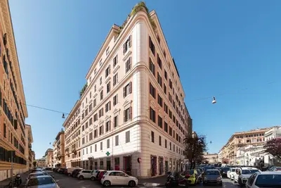 a tall white building with cars parked on a street at GuestHost - Rione Prati Apartments in Rome