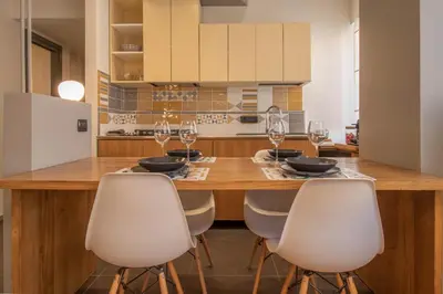 a kitchen with a wooden table and white chairs at Suite Color Family Roma in Rome