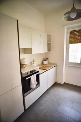 a small kitchen with white cabinets and a window at L'Oasi di Ale in Rome