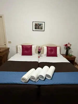 two beds in a room with red and blue sheets at Niam House Volturno in Rome