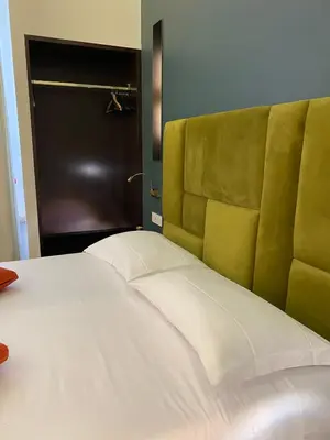 a bedroom with a large white bed with a green headboard at Unicum Trastevere Suites in Rome