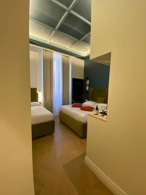 a hotel room with two beds and a mirror at Unicum Trastevere Suites in Rome