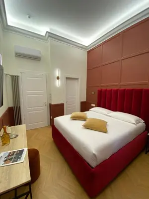 a bedroom with a large bed with a red headboard at Unicum Trastevere Suites in Rome