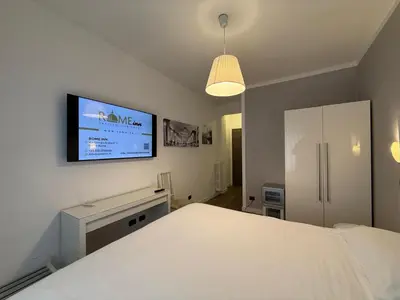 a bedroom with a white bed and a flat screen tv at Rome Inn Vatican View Rooms in Rome
